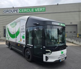 un camion noir, blanc et vert stationné devant un entrepôt