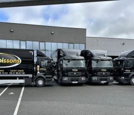 Quatre camions noir stationnés devant une entrepôt