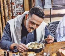 Un homme à table mange des pates à la cantine d'entreprise