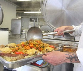 Un cuisinier devant une marmite avec un plat de légumes