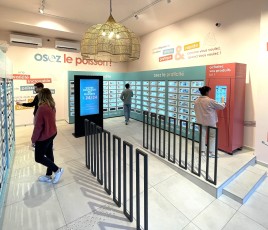 Quatre clients dans un local devant les écrans et les casiers d'une consigne automatique