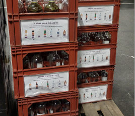 Caisses plastiques rouge contenant des bouteilles vides en verre sur une palette bois