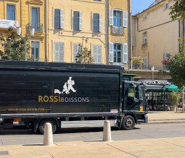 un poids lourd noir stationné devant une façade de couleur jaune clair.