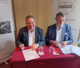 deux hommes signent un contrat ; deux kakémonos derrière eux