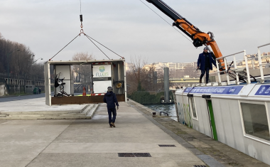 une grue décharge un caisson depuis une péniche vers un quai