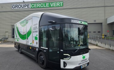 un camion noir, blanc et vert stationné devant un entrepôt