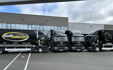 Quatre camions noir stationnés devant une entrepôt