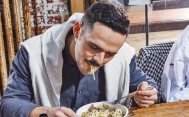 Un homme à table mange des pates à la cantine d'entreprise