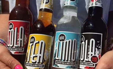 Quatre bouteilles de soft en gros plan tenues par deux mains