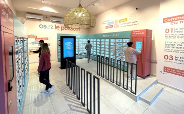 Quatre clients dans un local devant les écrans et les casiers d'une consigne automatique