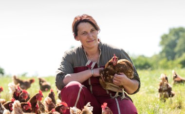 une fermière avec ses poules dans un champs