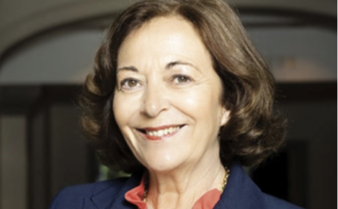 portrait d'une femme souriante cheveux châtains, veste bleue sur chemisier rouge. 