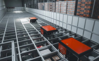 Trois automates rouges en position horizontale sur un meuble de rangement dans un entrepôt 