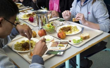 Enfants qui mangent à la cantine scolaire 