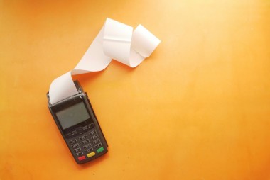 Terminal de paiement noir avec reçu blanc sur fond orange