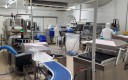 Ligne de conditionnement avec un tapis bleu au premier pan et un opérateur au fond à droite de l'image.