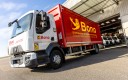Camion à caisse rouge en gros plan, à moitié sorti d'un garage.