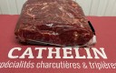 Amas de viande rouge sous film plastique, posé sur un à plat rouge avec le titre Cathelin juste en dessous.
