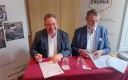 deux hommes signent un contrat ; deux kakémonos derrière eux