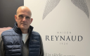 un homme chauve, habillé en bleu marine, debout à côté d'un kakemono d'entreprise 